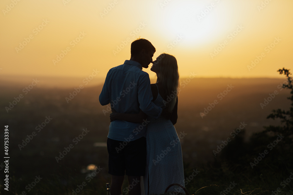 Attractive couple enjoying romantic sunset on picnic on the hill and want to kiss. Romantic evening in the amazing sunset. Copy space.