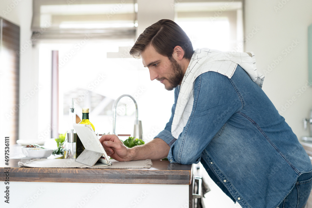 cooking, technology and home concept - man reading recipe from tablet pc computer. cooking, technology and home concept - man reading recipe from tablet pc computer.