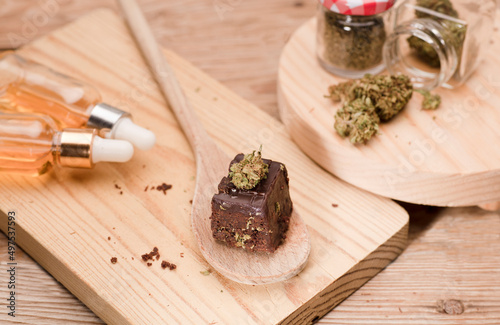 Marijuana brownie, kitchen with cans of oil and jars with buds, wooden table.