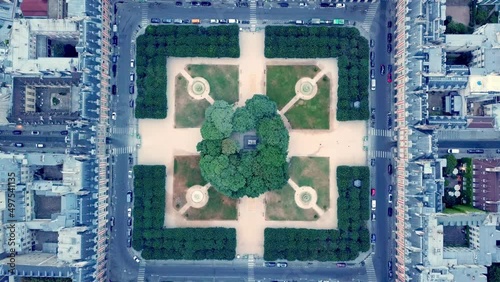 Top down static footage of symmetrical square Place des Vosges from drone. Park with clipped lindens surrounded by road and houses, Paris, France. photo