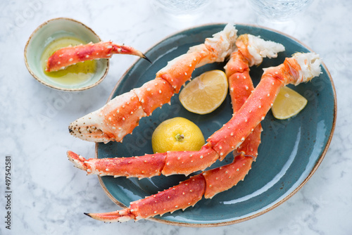 Turquoise plate with boiled kamchatka crab legs on a light-grey marble background, horizontal shot