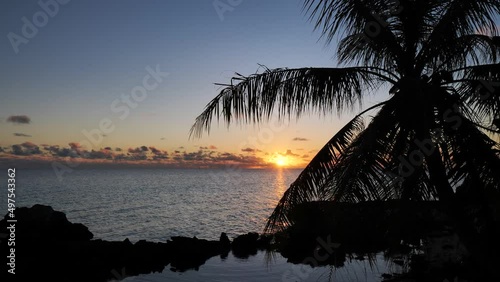 Long shot of sunset and evening sky over the Lagoon of Fakarava, French Polynesia, south pacific ocean with reflexions on the calm water surface. photo