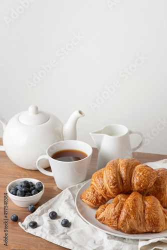 croissants with blueberries and tea on a wooden table