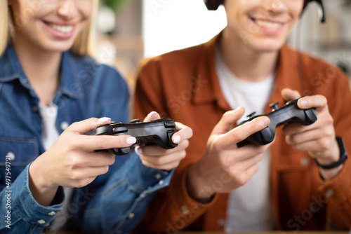 Games, entertainment, family, leisure concept. Close up of young Caucasian family hands, holding joysticks and enjoying their free time playing new games at home. Selective focus on hands