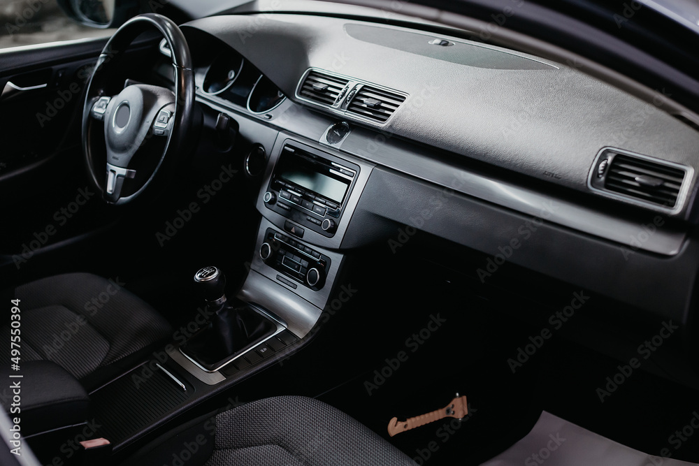 Modern car interior: steering wheel, gearshift lever, multimedia system and dashboard.