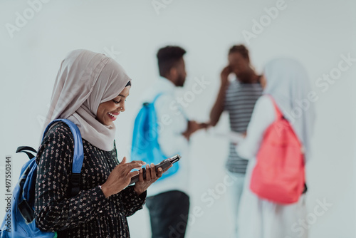 African female student with group of friends in background wearing traditional Islamic hijab clothes. Selectve focus  photo