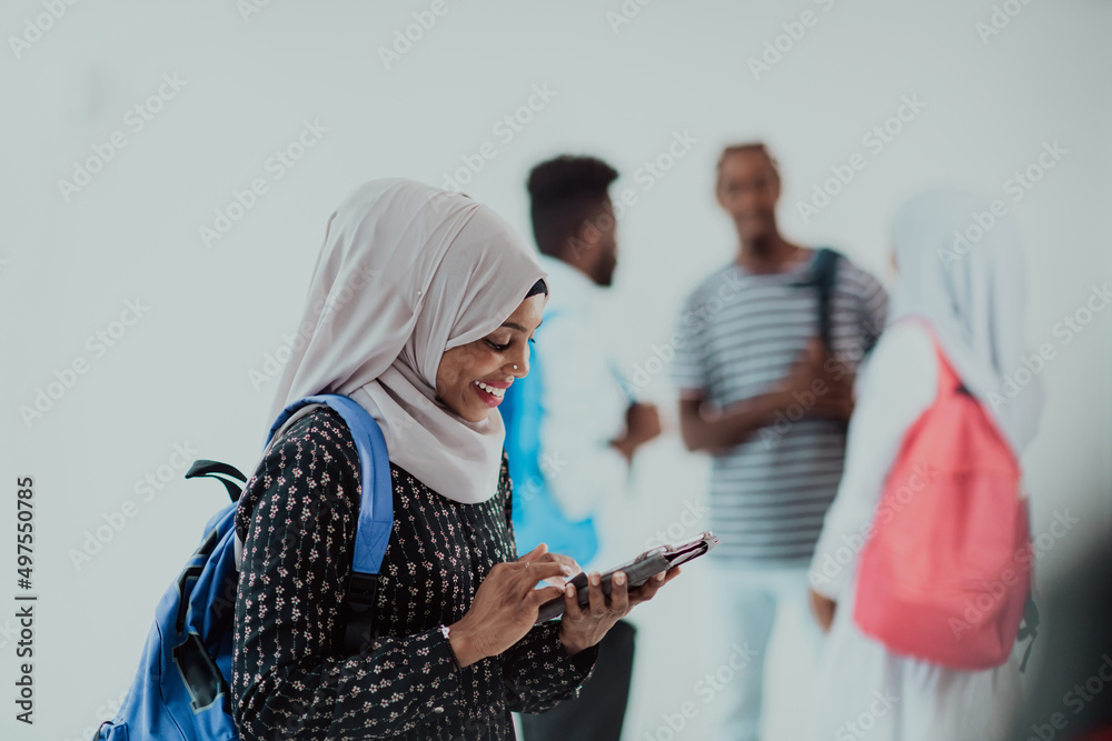 African female student with group of friends in background wearing traditional Islamic hijab clothes. Selectve focus 