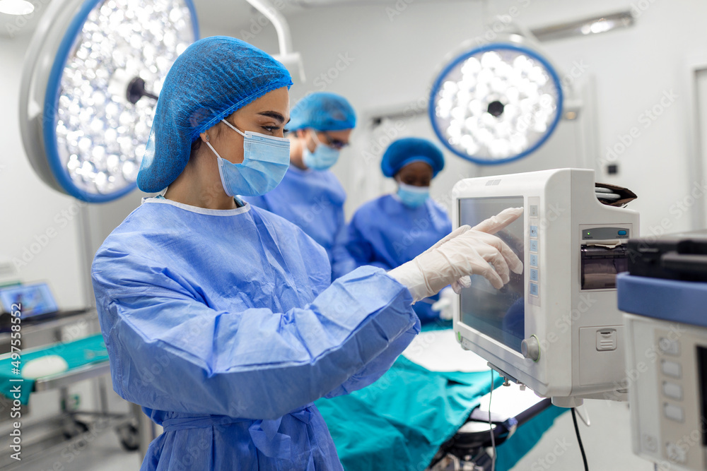 Anesthesiologist keeping track of vital functions of the body during cardiac surgery. Surgeon looking at medical monitor during surgery. Doctor checking monitor for patient health status. Anesthesiologist keeping track of vital functions of the body during cardiac surgery. Surgeon looking at medical monitor during surgery. Doctor checking monitor for patient health status.