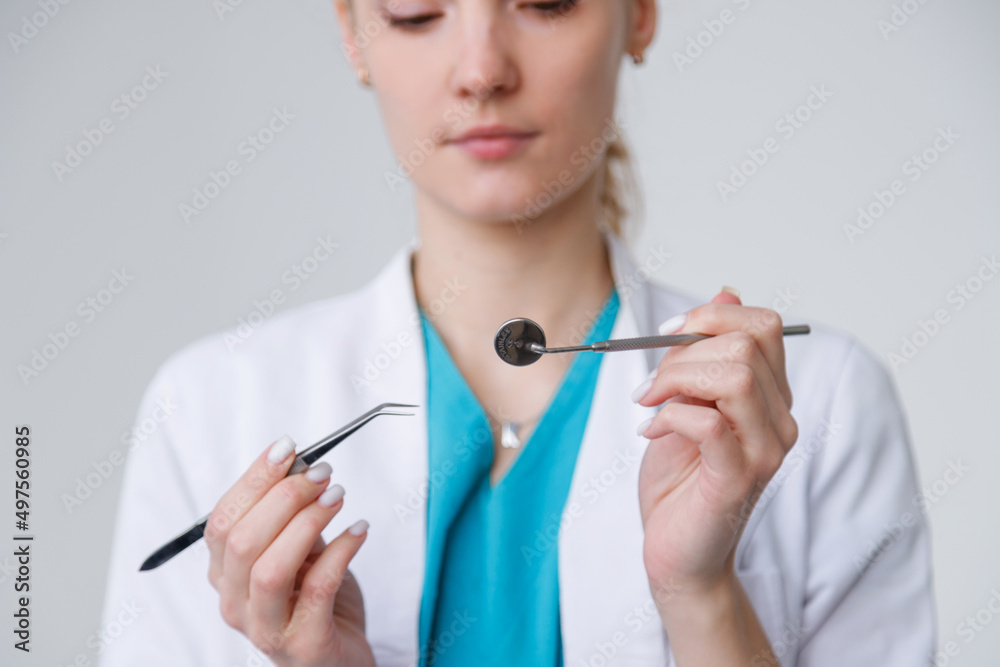 Young dentist with tools mirror and tweezers on white background Young dentist with tools mirror and tweezers on white background