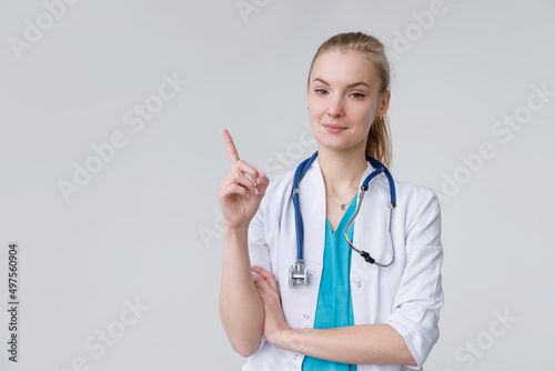 Young european woman wearing doctor with stethoscope pointing with finger up  gesture paying attention
