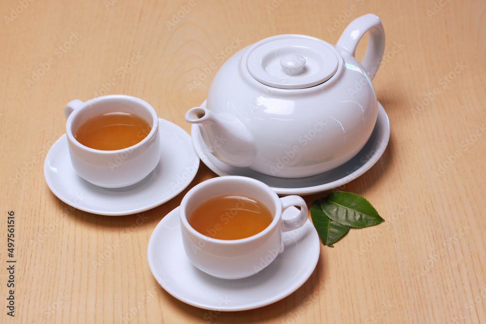 Hot white tea set of cups, teapot and fresh leafs isolated on wooden table