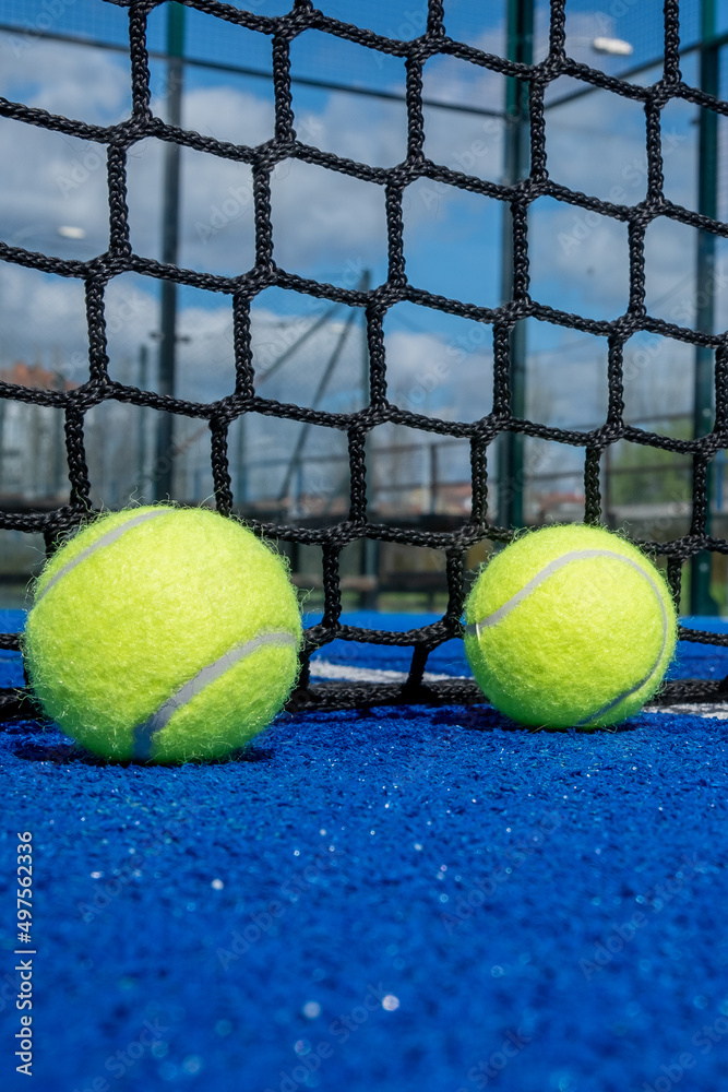 two balls near the net in a blue paddle tennis court