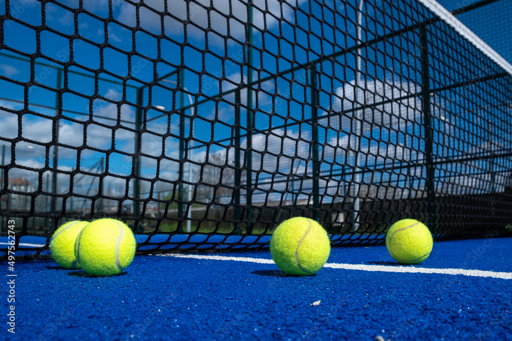 three balls near the net in a blue paddle tennis court