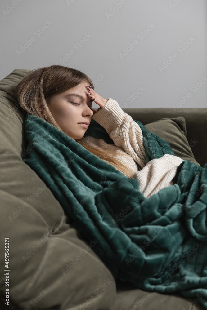 A woman lying on a sofa has a headache and she touches her forehead A woman lying on a sofa has a headache and she touches her forehead