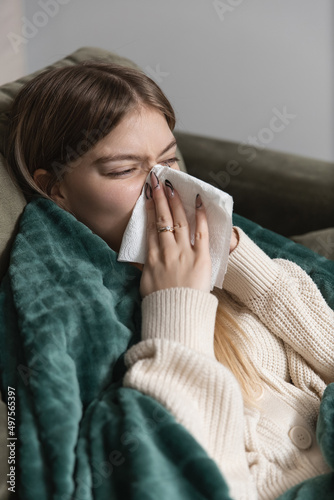 The girl is sick and wipes her nose with a paper napkin