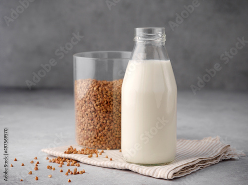 Buckwheat groats, buckwheat flour and vegan buckwheat milk on a gray background, gluten-free concept. Ingredients for porridge. An idea for a healthy gluten-free breakfast. Non dairy alternative milk.