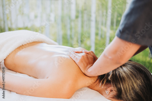 Unrecognizable therapist making a back and neck massage to a face down female patient. Wellness center spa.