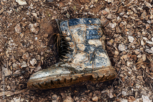 one soldiers boot in the mud. dirty boots on the ground. Losses in battle photo