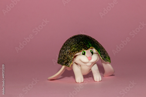 cute toy rabbit with a beautiful painted egg shell on her head, creative easter design with copy space