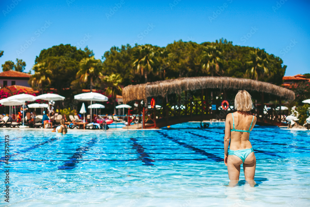 Woman in blue bikini standing in the swimming pool