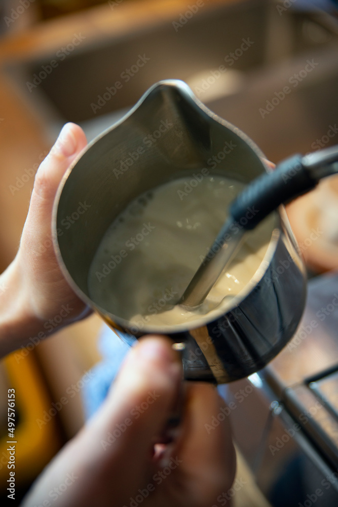 Barista texturing milk in a stainless steel jug