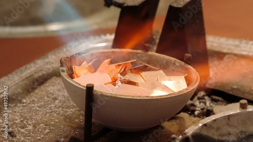 Goldsmith melting gold to liquid state in crucible with gasoline burner