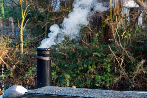 A smoke stack on a narrow boat keeping the crew warm on a winter’s day.  next to a modern solar pan the Lee and Stort canal at Sawbridgeworth