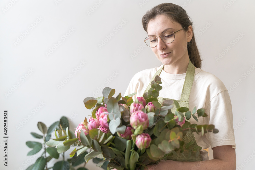 Portrait of a professional florist of a young woman in glasses with a bouquet of bright flowers. The concept of small business and young entrepreneur Portrait of a professional florist of a young woman in glasses with a bouquet of bright flowers. The concept of small business and young entrepreneur