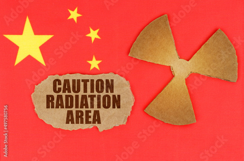 On the flag of China  the symbol of radioactivity and torn cardboard with the inscription - caution radiation area