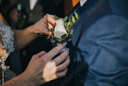 Billede på lærred Closeup shot of the bride pinning the corsage to her groom