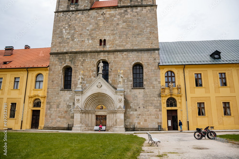 Tepla, Czech Republic, 7 August 2021: Premonstratensian Abbey and monastery, Romanesque church of the Annunciation with towers, gothic arched portal with stone carved statues of saints at summer day