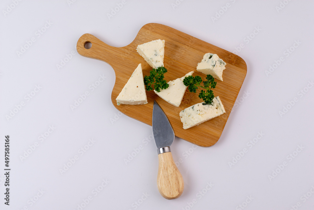 Slice of Roquefort cheese on board isolated on white background