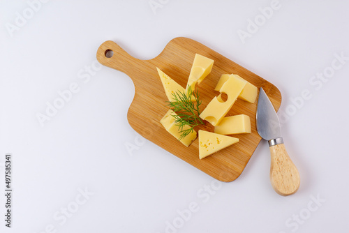 triangular piece of yellow cow's milk swiss cheese with holes cutout on cutting board, isolated white background photo