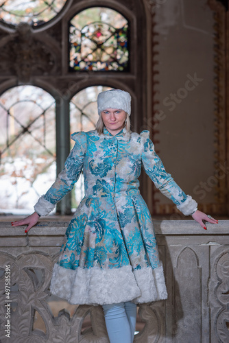 A beautiful woman in a winter coat and winter hat (Ushanka). A beautiful woman in an abandoned castle.