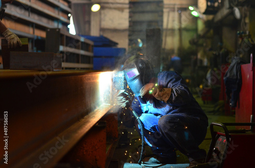 Workers wearing industrial uniforms and Welded Iron Mask at Steel welding plants, industrial safety first