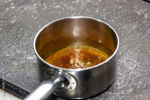 The cook cooks caramel from sugar in a saucepan