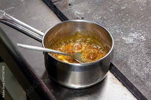 The cook cooks caramel from sugar in a saucepan photo