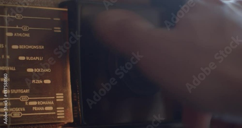 The hand turns the radio tuning knob in the evening. Looking for an interesting wave to listen to. Index of radio stations by cities.