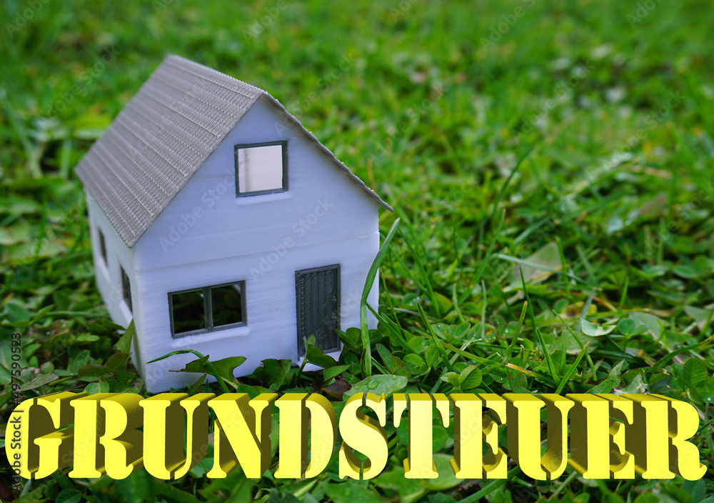 ein Haus auf einer Wiese mit dem Schriftzug Grundsteuer Stock Photo