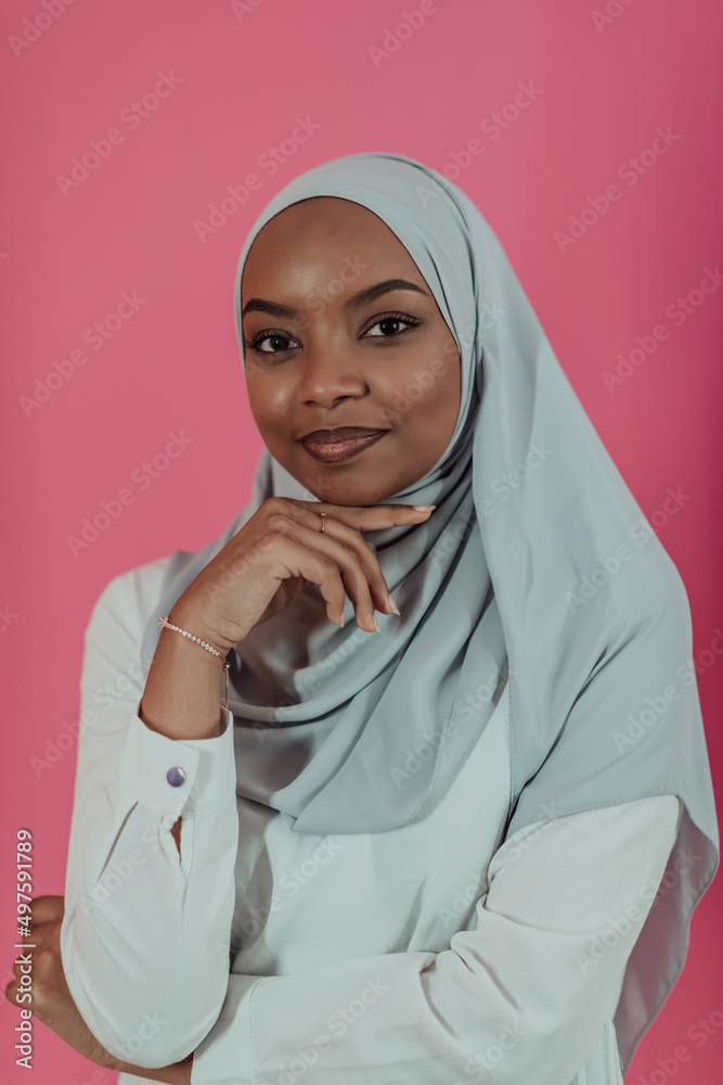 Portrait of young modern muslim afro beauty wearing traditional islamic clothes on plastic pink background. Selective focus Portrait of young modern muslim afro beauty wearing traditional islamic clothes on plastic pink background. Selective focus