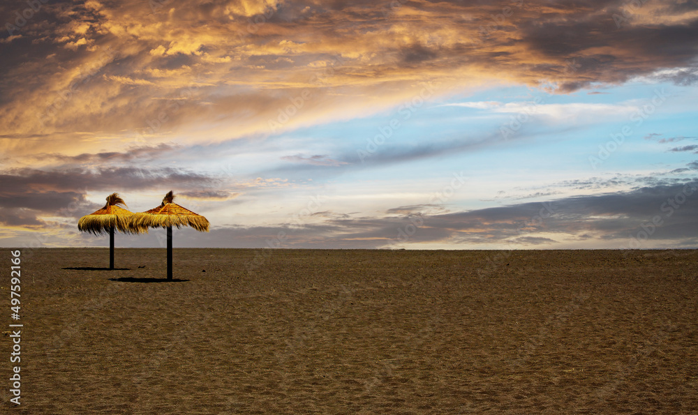 View on deserted tropical sand beach with two umbrellas, storm clouds - early booking preseason rate concept