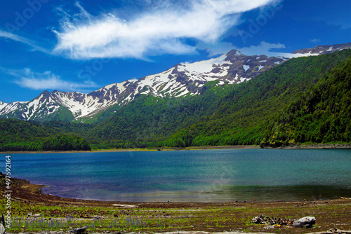Fototapeta Naklejka Na Ścianę i Meble -  View over isolated crater lake on partly black snow capped Volcano Llaima contrasting with blue sky -  Conguillio NP in central Chile;