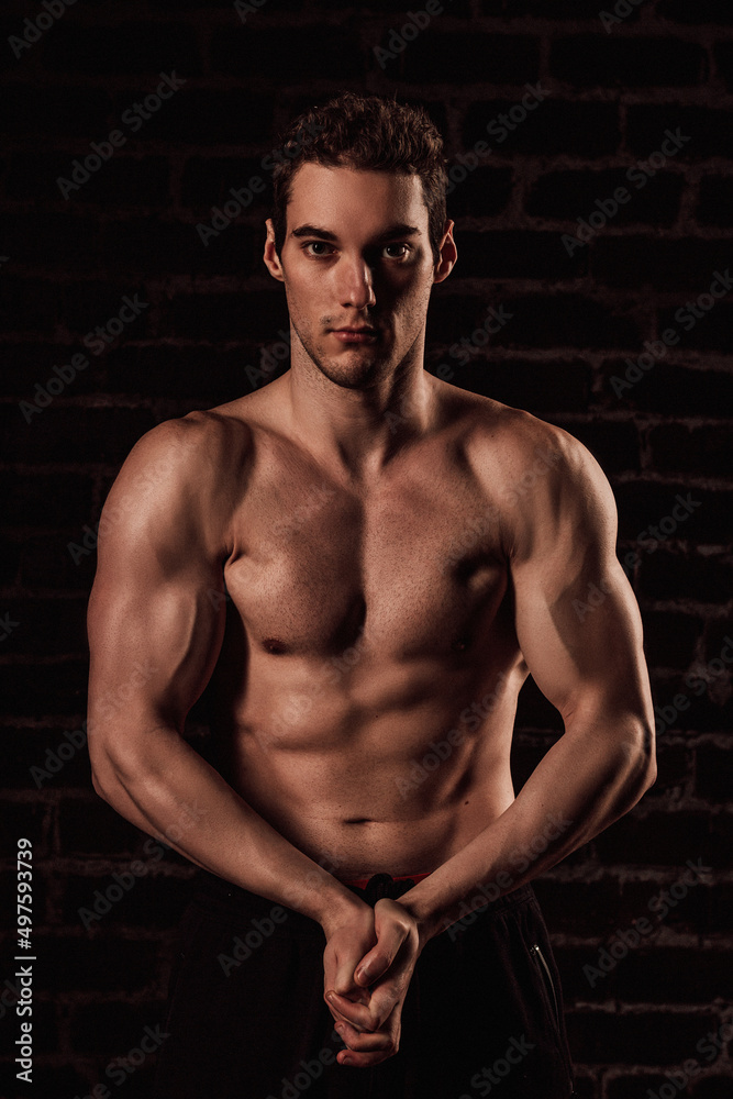 Naked torso of a young handsome man on a dark background Naked torso of a young handsome man on a dark background