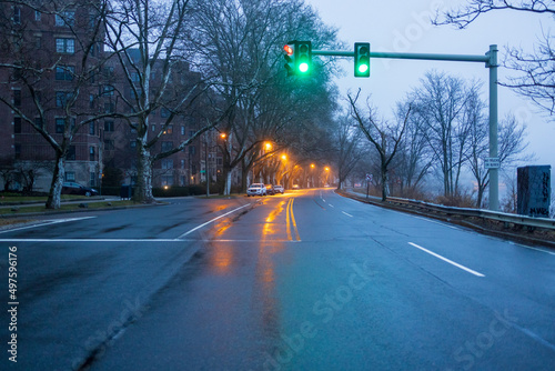 Streetlights reflect off wet street at dawn