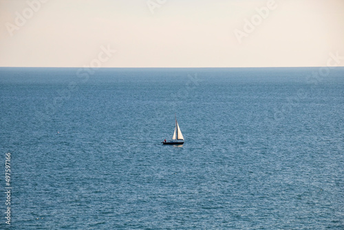 Little white boat in the middle of the blue sea with the horizon and blue sky © nomadkate