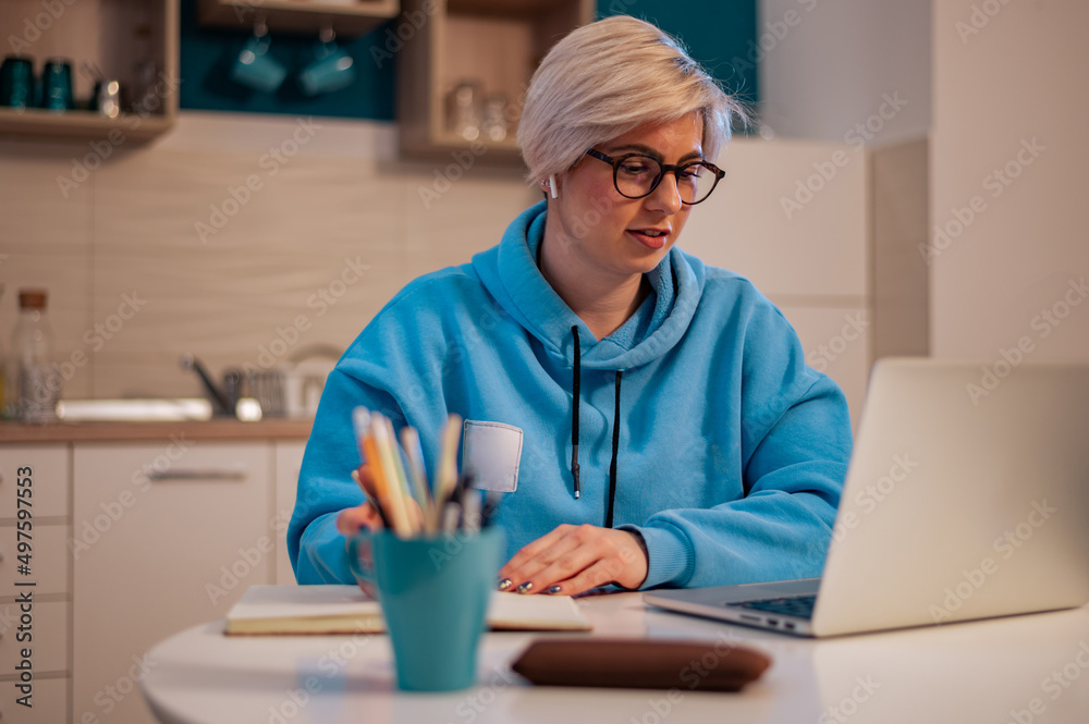 Woman working on a laptop in the kitchen at home Woman working on a laptop in the kitchen at home