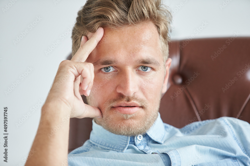 Portrait of a stylish intelligent man, small unshaven, charismatic, blue shirt, sitting on a brown leather chair, dialog, negotiation, short sleeve, brutal, hairstyle, emotions, energy, interest Portrait of a stylish intelligent man, small unshaven, charismatic, blue shirt, sitting on a brown leather chair, dialog, negotiation, short sleeve, brutal, hairstyle, emotions, energy, interest