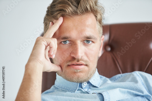 Wallpaper Mural Portrait of a stylish intelligent man, small unshaven, charismatic, blue shirt, sitting on a brown leather chair, dialog, negotiation, short sleeve, brutal, hairstyle, emotions, energy, interest Torontodigital.ca