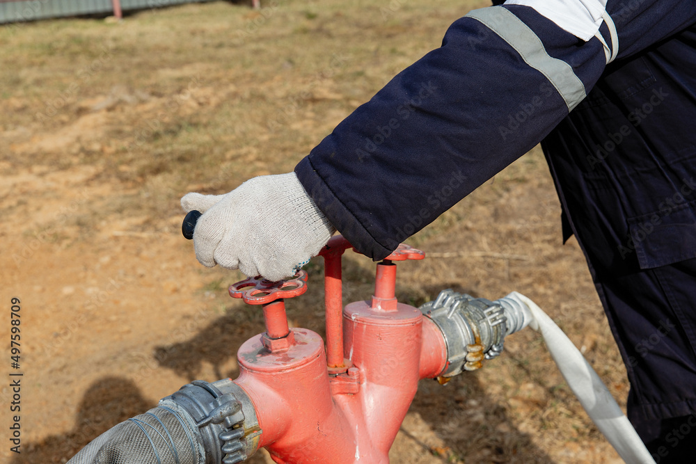 Obraz premium Fire hydrant column for fire extinguishing water supply. Connecting the hydrant.