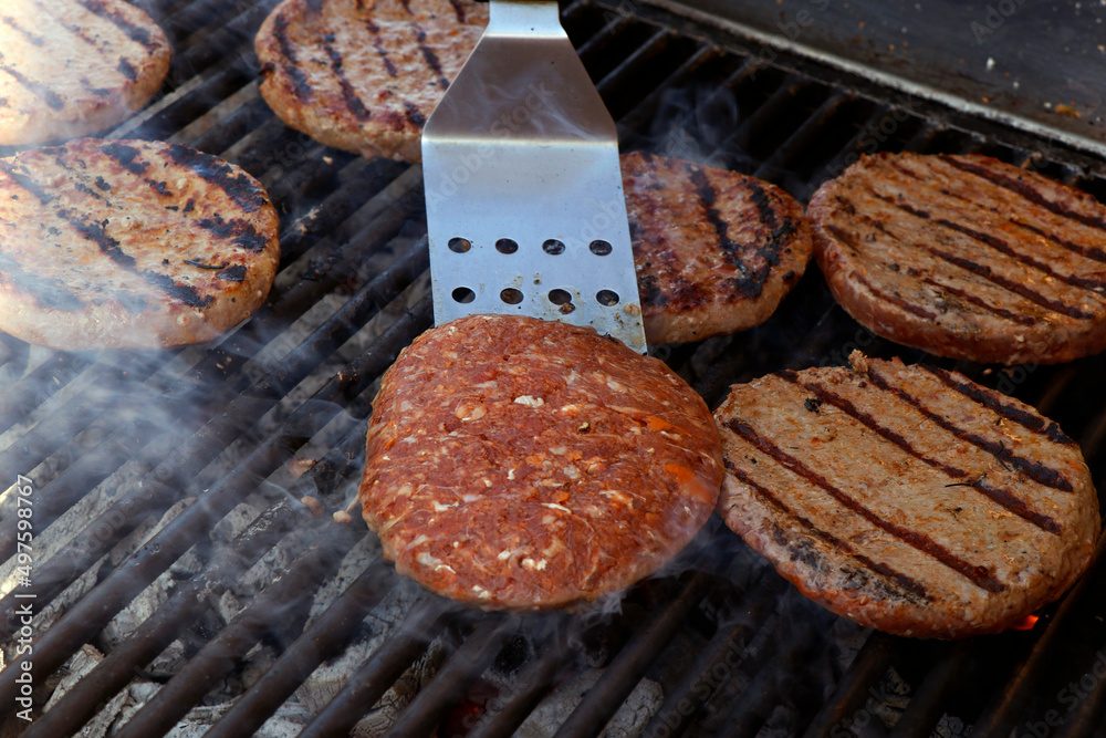 beef meat burger patty on a hot smoky barbeque grill